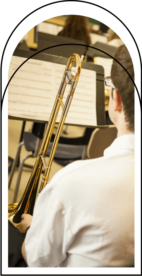 Étudiant jouant du trombone, partitions visibles, pratique musicale en groupe, ambiance académique, exploration artistique, apprentissage instrumental, harmonie collective, environnement éducatif.