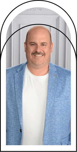 David Girard, ancien élève et parent d’élèves de la Fondation Saint-Sacrament, portrait professionnel, veston bleu et t-shirt blanc, sourire chaleureux, fond neutre, engagement communautaire, contribution active aux initiatives éducatives et sociales.