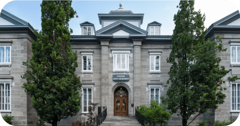 Façade principale du Collège Saint-Sacrament, bâtiment historique en pierre, entouré d’arbres, architecture classique, entrée centrale, escalier, ciel dégagé, représentation de l’établissement éducatif, Fondation Saint-Sacrament.