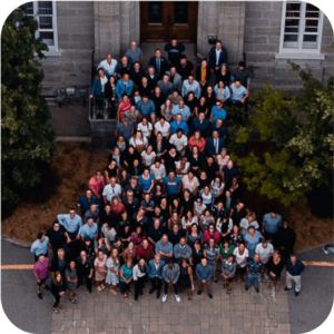 Photo aérienne d’un grand groupe de partenaires et donateurs devant le bâtiment historique du Collège Saint-Sacrament, rassemblement extérieur, collaboration communautaire, engagement pour l’éducation, soutien des initiatives de la Fondation Saint-Sacrament.